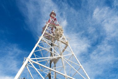 Telecommunication tower with antennas against blue sky clipart