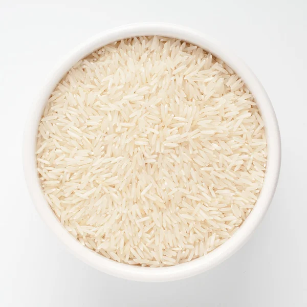 Beyaz zemin üzerinde bir seramik kase çiğ basmati pirinç — Stok fotoğraf