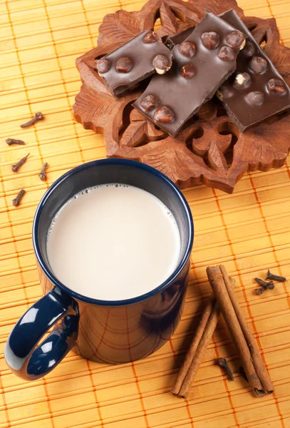 Copa de cacao caliente con una barra de chocolate, canela y clavo de olor — Foto de Stock