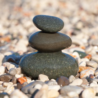 Pyramid made with wet pebble stones on the sea beach clipart