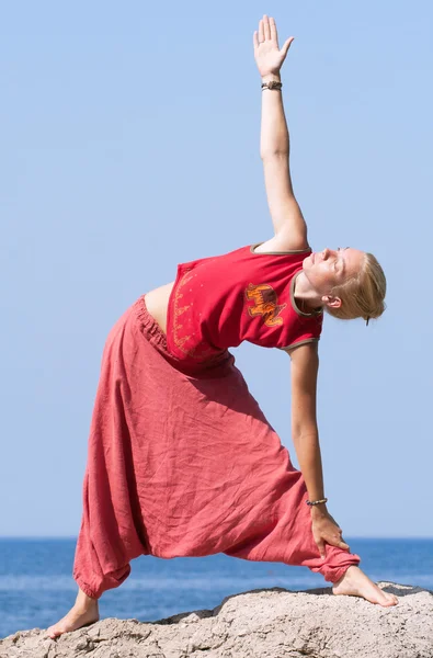 Όμορφη κοπέλα κάνει ασκήσεις γιόγκα σε ένα βράχο δίπλα στη θάλασσα — Φωτογραφία Αρχείου