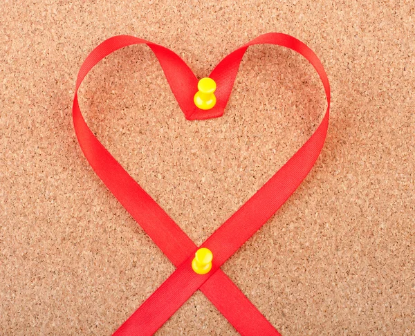 Rode hartvormige lint vastgemaakt om cork board — Stockfoto