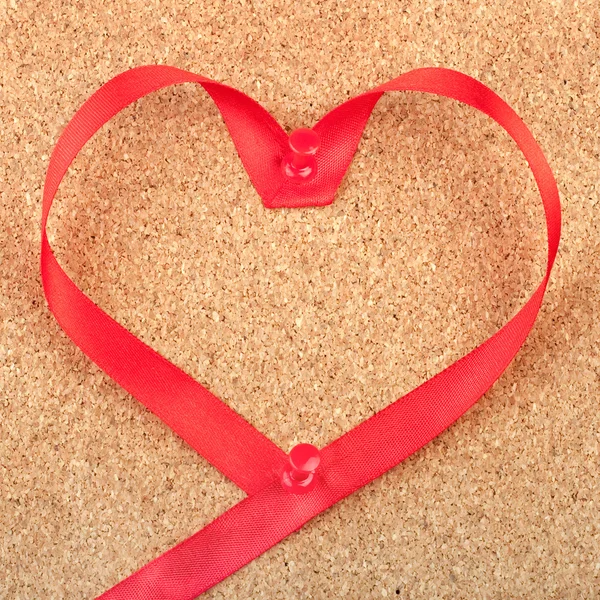 Ruban rouge en forme de coeur épinglé sur le panneau de liège — Photo