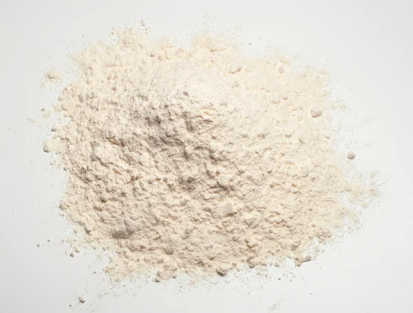 Farinha de trigo amontoado em um fundo branco — Fotografia de Stock