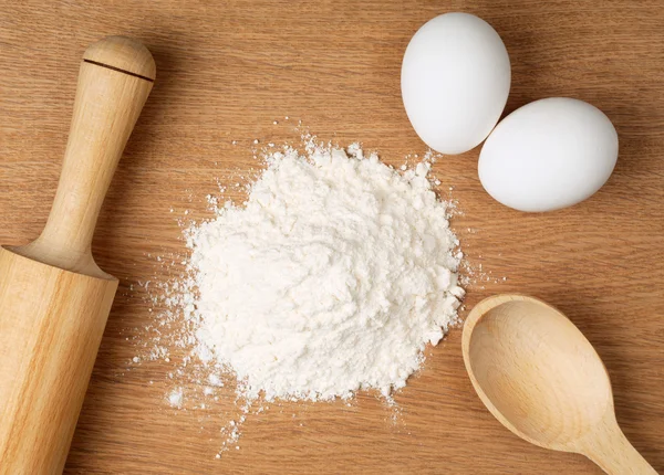 Farinha e ovos numa tábua de madeira — Fotografia de Stock