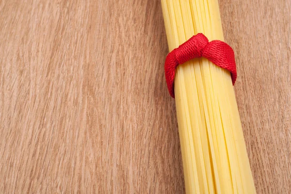 Spagetti csomó megkötött megjelöl-val egy piros szalag, a fából készült backgro — Stock Fotó
