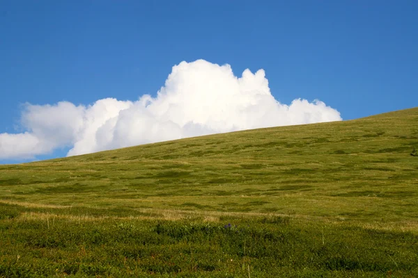 Λευκό σύννεφο πίσω από το καλοκαίρι πράσινο λόφο — Φωτογραφία Αρχείου
