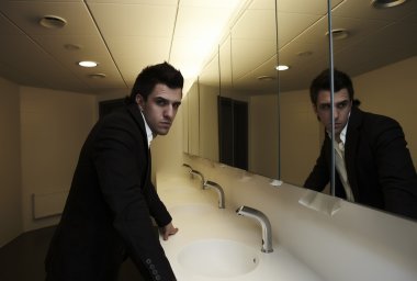Vain business man checking his looks in the mirror clipart
