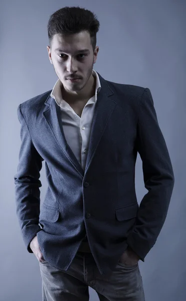 Mladý atraktivní muž v obleku na šedém pozadí — Stock fotografie