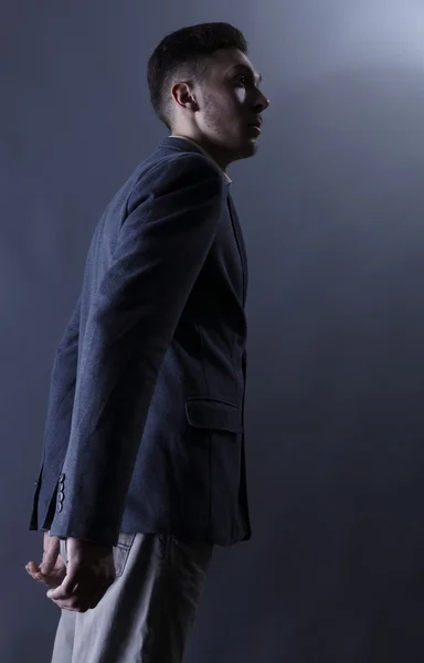 Unga attraktiva mannen i kostym på grå bakgrund — Stockfoto