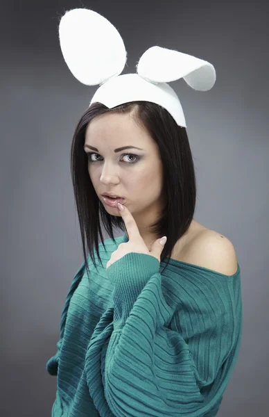 Morena engraçada em uma camisola brilhante com orelhas de coelho na cabeça . — Fotografia de Stock