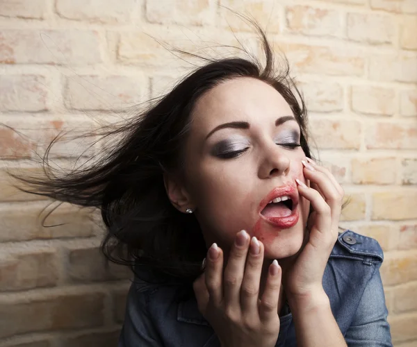 Depressed young brunette with smeared lipstick on her face. — Stock Photo, Image
