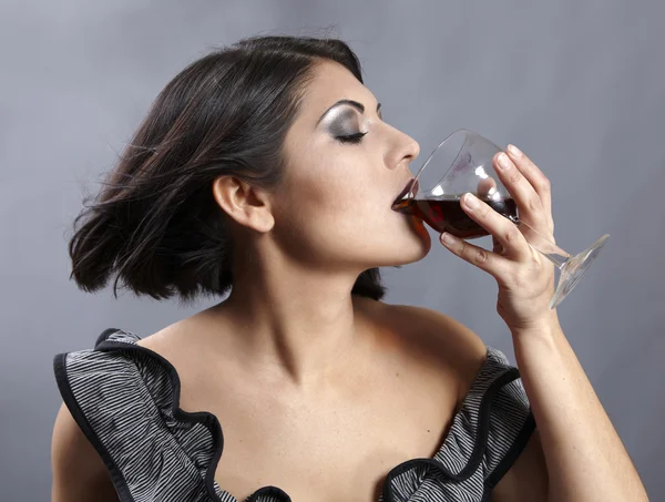 Studio portrait of beautiful brunette holding a glass wine. — Stock Photo, Image