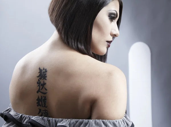 Portrait of a pretty girl with tattoo on her back — Stock Photo, Image
