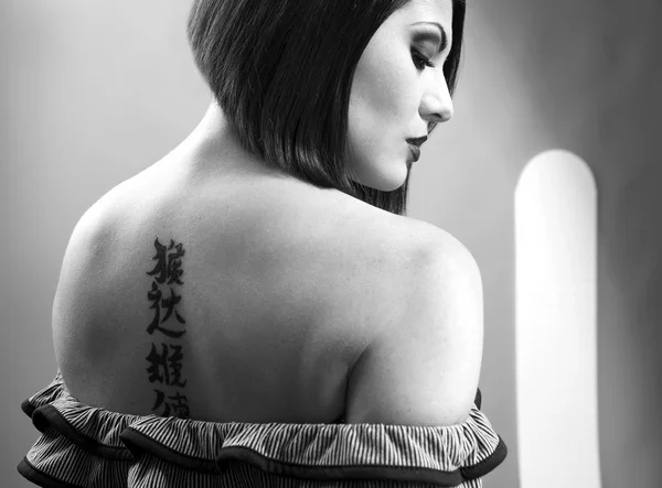 Porträtt av en söt flicka med tatuering på hennes rygg — Stockfoto