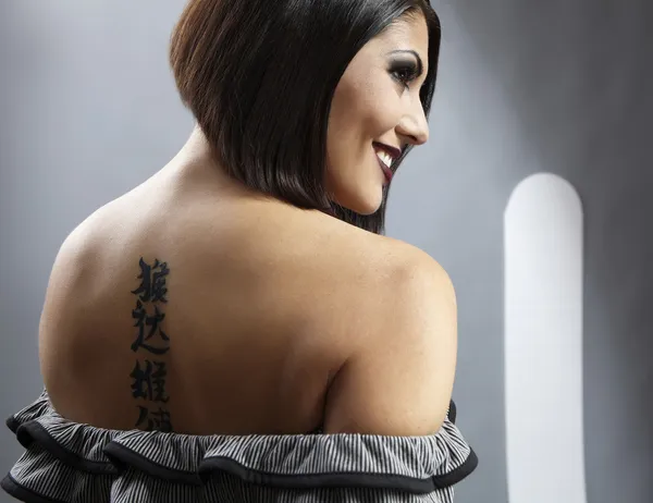 Portrait of a pretty girl with tattoo on her back — Stock Photo, Image