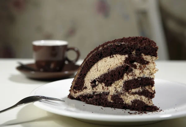 Schokoladenkuchen auf dem weißen Teller mit einer Tasse Kaffee — Stockfoto