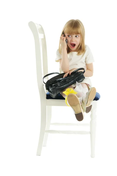 Sandalyenin üstünde telefon ile sürpriz kız — Stok fotoğraf