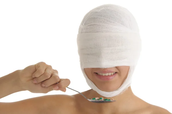 Mujer con la cabeza vendada con tabletas en cuchara — Foto de Stock