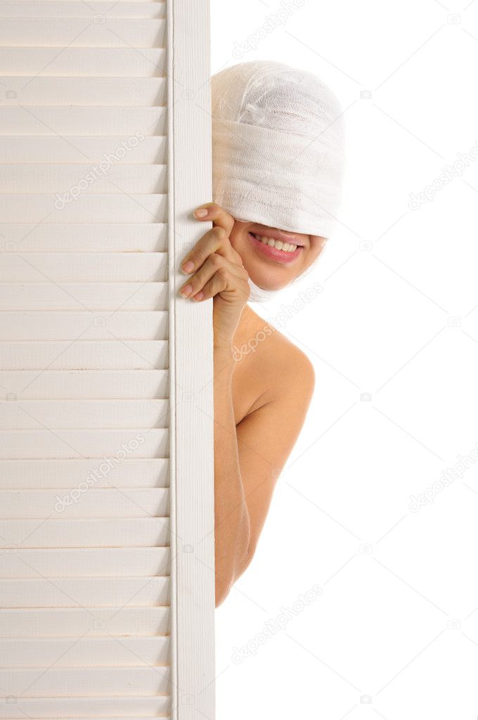 Young woman looks out because of door isolated in white