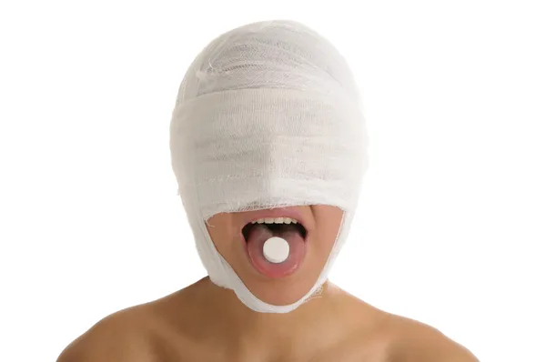 Junge Frau Mit Bandagiertem Kopf Mit Tablette Der Zunge Isoliert — Stockfoto