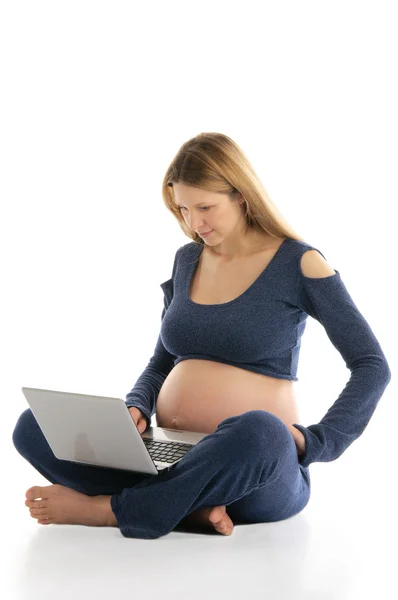 Gravid kvinna med en laptop sitter på golvet — Stockfoto