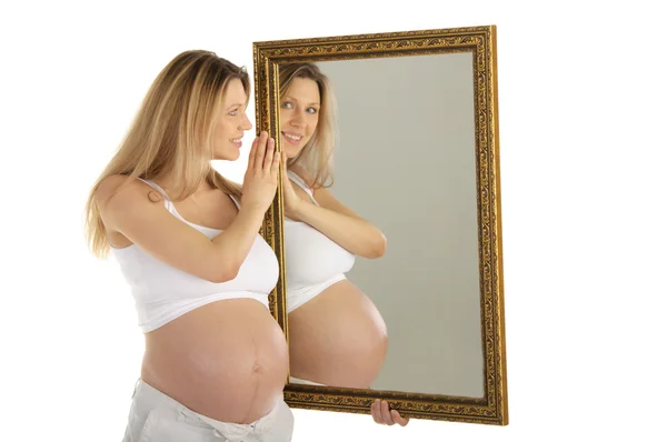 Zwangere vrouw kijkt in de spiegel — Stockfoto