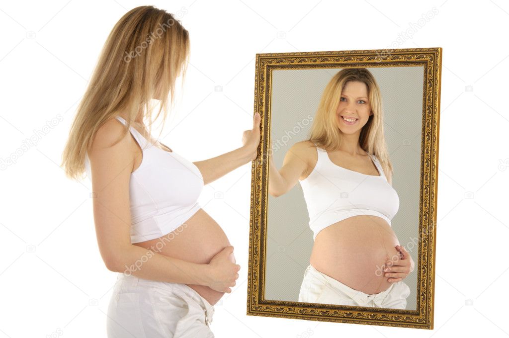Pregnant woman looks in the mirror isolated on a white