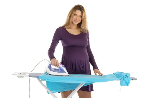Pregnant woman in a purple dress with an iron — Stock Photo, Image