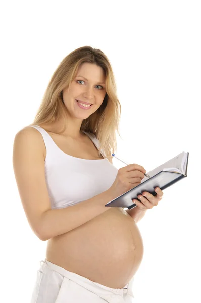 Mutlu bir hamile kadın bir not defterine yazdı. — Stok fotoğraf