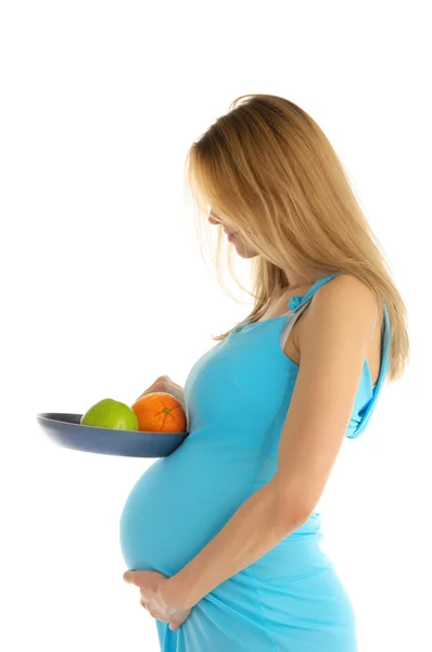 Zwangere holding een appel en een oranje in een pan — Stockfoto
