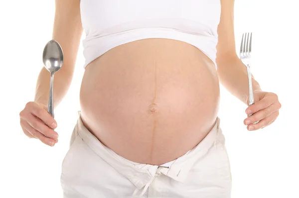 Žaludky těhotných žen s lžící a vidličkou — Stock fotografie