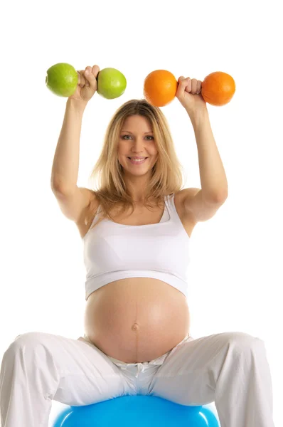 Беременная занимается фитнесом гантели фрукты — стоковое фото