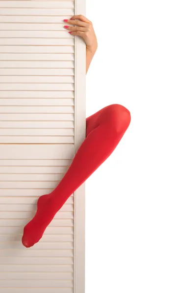 Vrouwelijke voeten in rode kousen, handen en deur — Stockfoto