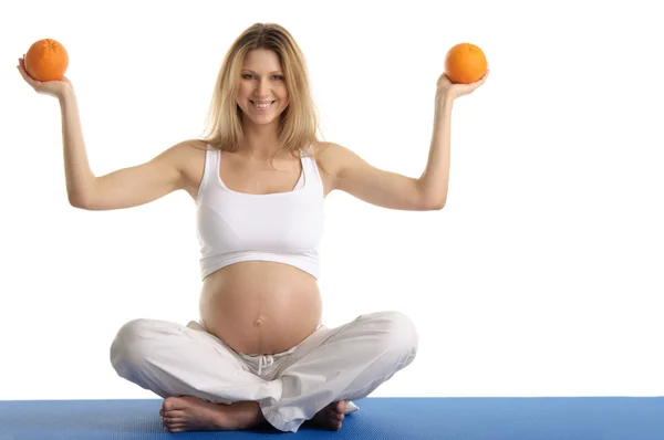 Mulher grávida praticando ioga com laranjas — Fotografia de Stock