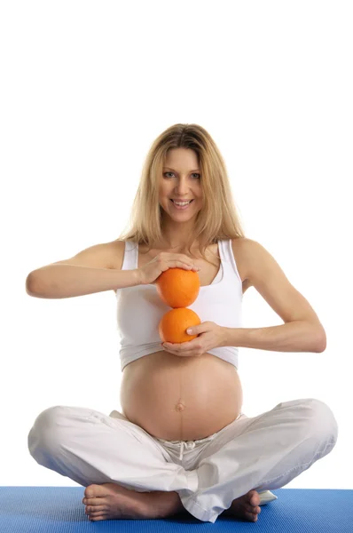 Mujer embarazada practicando yoga con naranjas — Foto de Stock