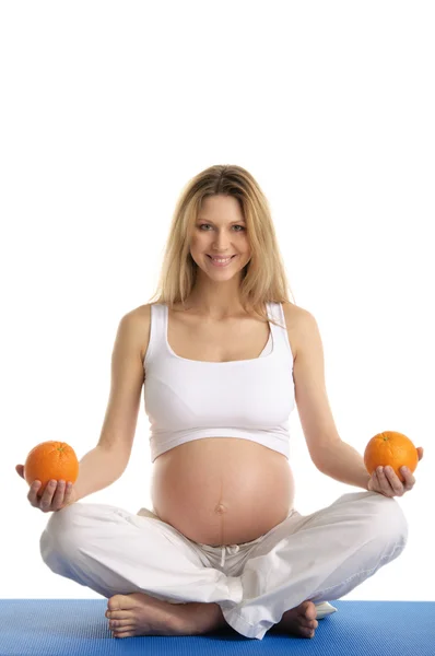Donna incinta che pratica yoga con arance — Foto Stock