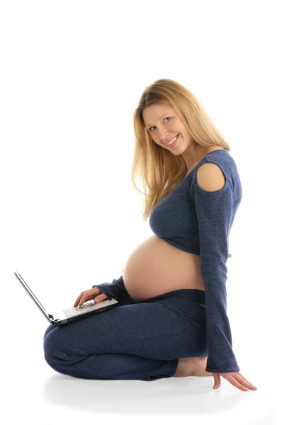 Katta oturan bir dizüstü bilgisayar ile hamile kadın — Stok fotoğraf