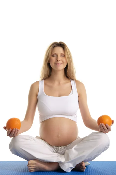 Schwangere praktiziert Yoga mit Orangen — Stockfoto