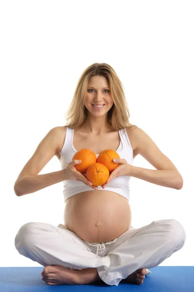 Zwangere vrouw beoefenen van yoga met sinaasappelen — Stockfoto
