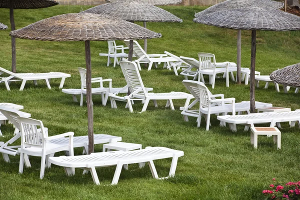 Lehátka a slunečníky na trávě v areálu hotelu — Stock fotografie
