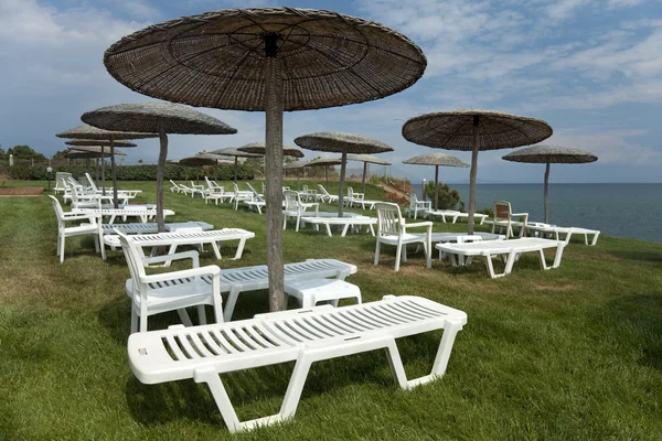 Liegestühle und Sonnenschirme auf der Wiese im Hotelbereich — Stockfoto