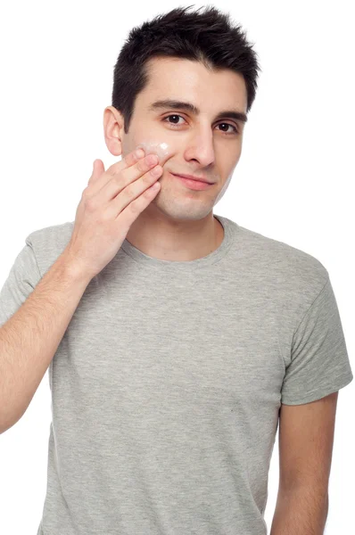 Hombre joven aplicando crema loción — Foto de Stock