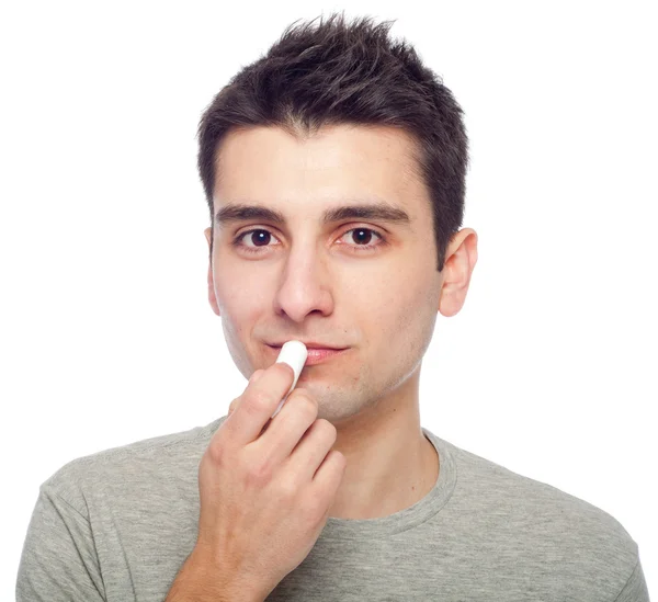 Молодой человек применяет бальзам для губ — стоковое фото