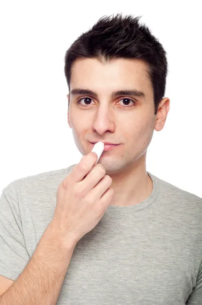Молодой человек применяет бальзам для губ — стоковое фото