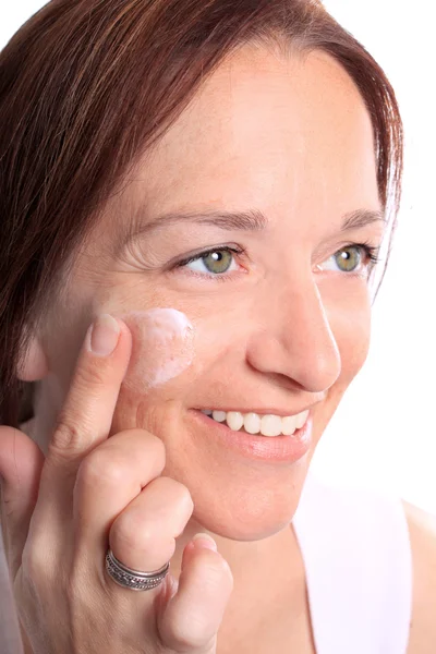 Adult woman applies cream on face — Stock Photo, Image