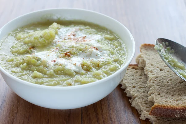 碗的绿色蔬菜汤和几桌上的面包切片 — 图库照片