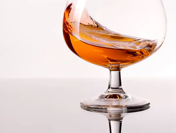 Cognac spritzt in ein Glas — Stockfoto