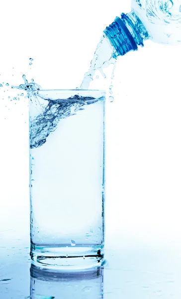 A água é derramada de uma garrafa em um copo — Fotografia de Stock