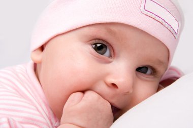 Baby girl looks unconcerned as long as her thumb is in her mouth. Closeup with blanket hugged to her face. clipart